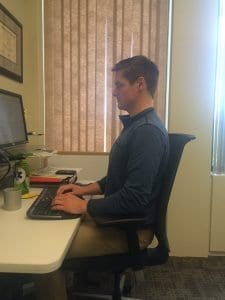 Example of how to sit properly in a desk. Notice how the posture keeps the spine upright.