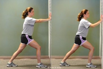 girl stretching ankle against wall